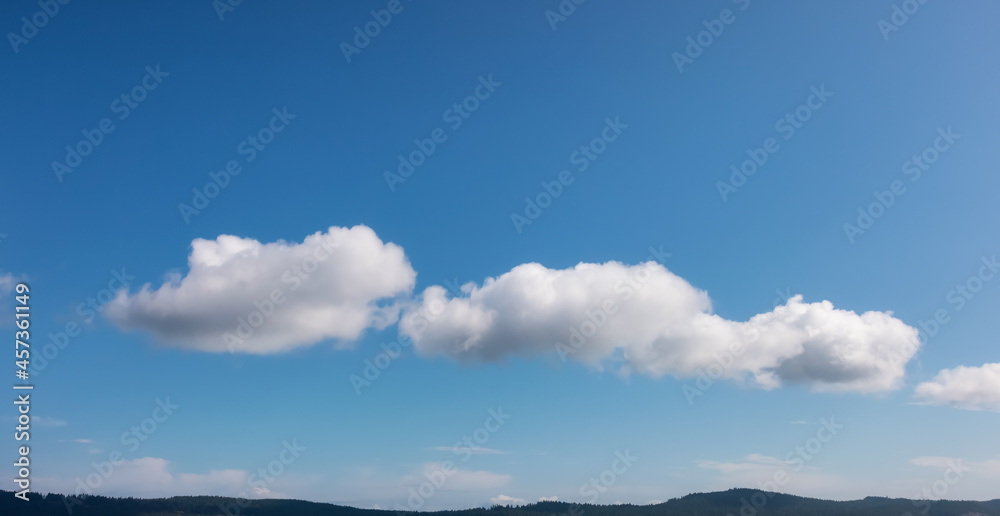 Panoramic View of Puffy White Clouds with Blue Sky during a beautiful Sunny Summer Day. Taken over the coast of British Columbia, Canada. Nature Background Panorama