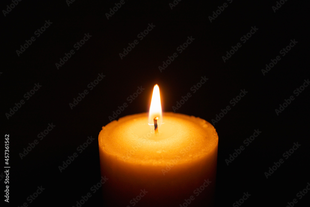One single light candle burning brightly in the black background.Spiritual candle yellow flame. Flame of candle in the darkness.Copy space. One single light candle burning brightly in the black background.Spiritual candle yellow flame. Flame of candle in the darkness.Copy space.