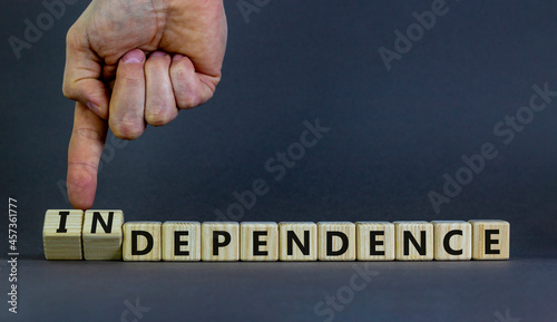 Dependence or independence symbol. Businessman turns cubes and changes the word 'dependence' to 'independence'. Beautiful grey background, copy space. Business, dependence or independence concept.