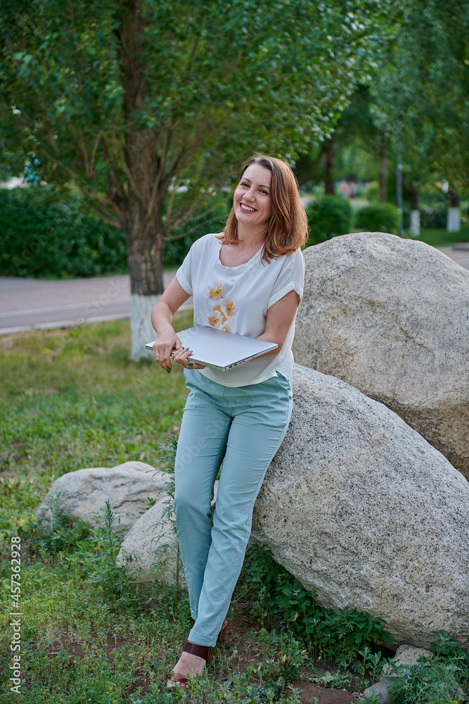 woman in trousers on the lawn with laptop