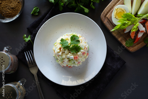 Crab salad with eggs, apple, crab sticks, celery seasoned with mayonnaise and spices on a white plate, horizontal, rustic, top view