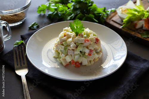 Crab salad with eggs, apple, crab sticks, celery seasoned with mayonnaise and spices on a white plate, horizontal, rustic 