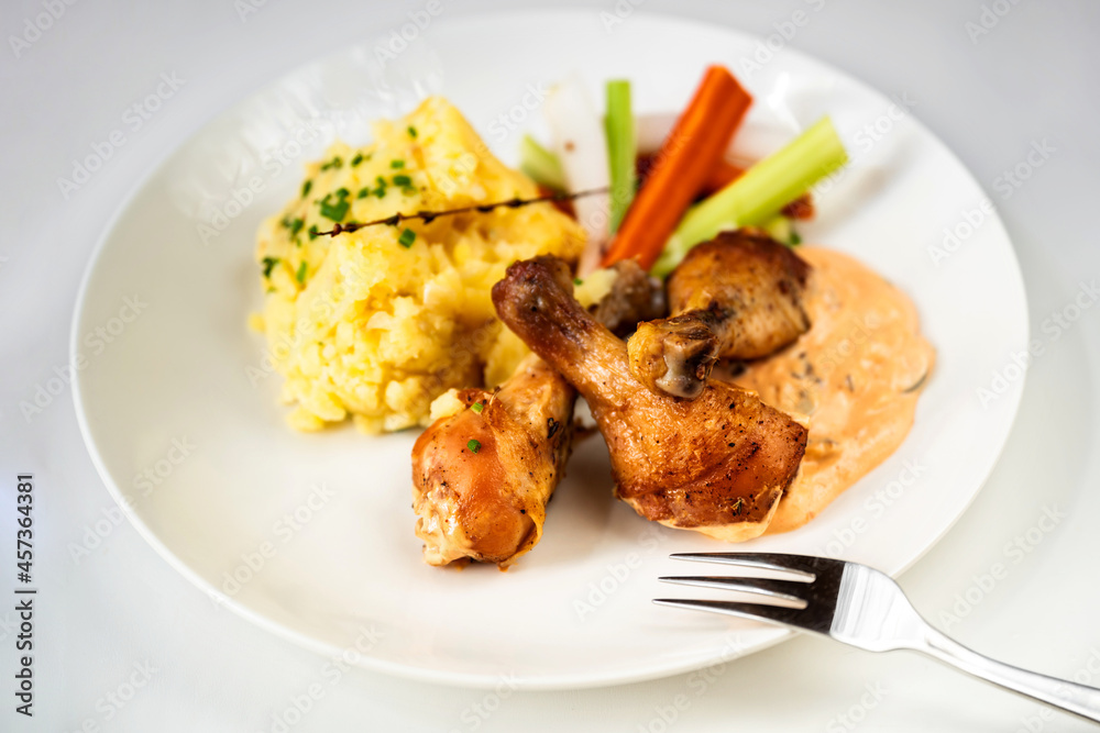 Chicken thig, mashed potato, olive mayonnaise and vegetable on white plate.