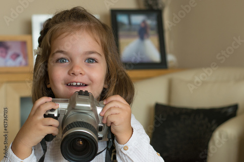 Child Taking A Picture. A Child Pretending To Take A Photograph With A Reflex Camera. Little Girl Playing With Camera In Her Living Room