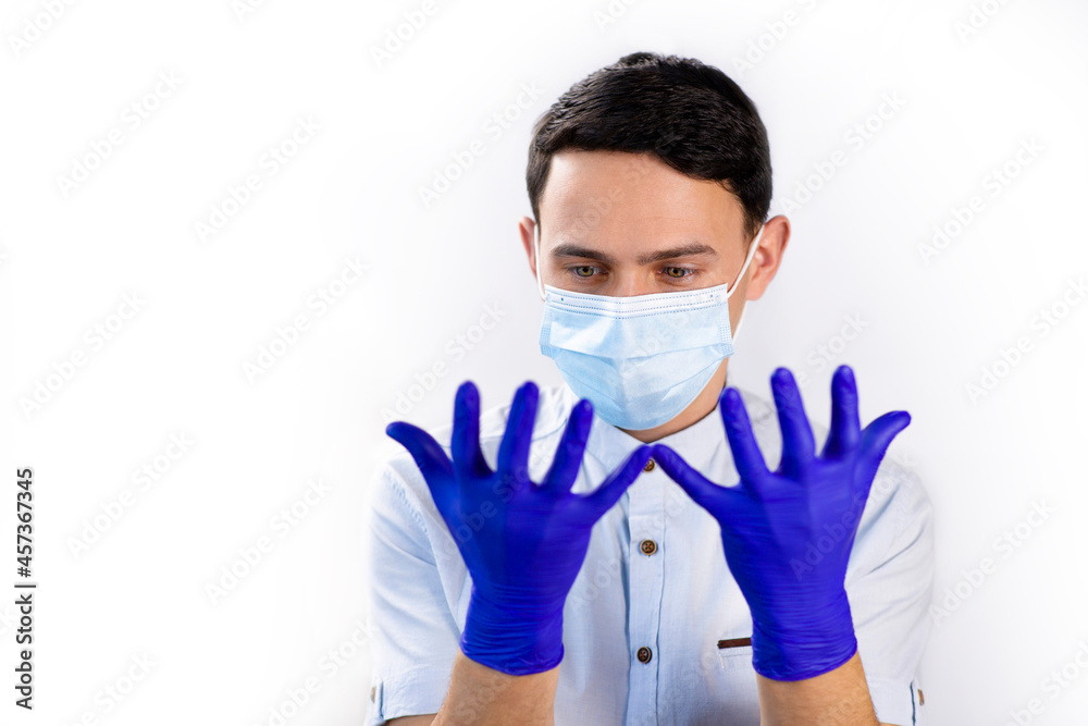 The guy in the medical mask and gloves. Virus protection. Precautionary Methods. Doctor on a white background. Blue medical gloves. The guy in the medical mask and gloves. Virus protection. Precautionary Methods. Doctor on a white background. Blue medical gloves.