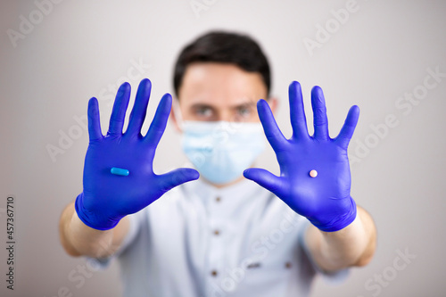 The guy in the protective mask and gloves. Pills in outstretched hands. One tablet in each hand. Medicines in hand. Doctor with medicines. Tablets to choose from.