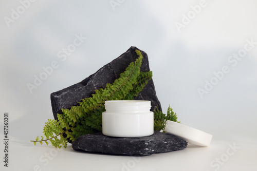 Unbranded natural cosmetic cream packaging standing on stone podium. Cream presentation on the white background. Mockup. Trending concept in natural materials. Natural cosmetic, skincare.