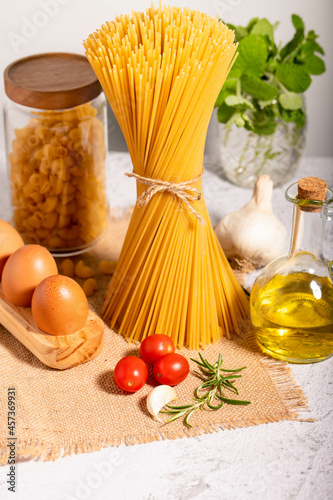 Carbo-diet - spaghetti, ditalini pasta together with a jar of olive oil, cherri tomatoes, garlic and eggs in eco-wooden palette.