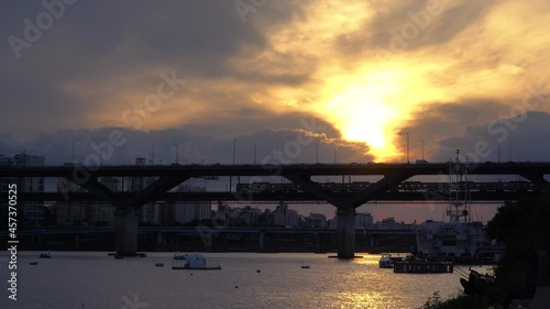 Subway Train Silhouette Moving Over Han River at Cheongdam Bridge When Golden Sun Goes Down to the Horizon at Sunset Seoul. Duplex bridge at evening twilight. Public transportation system of Seoul photo