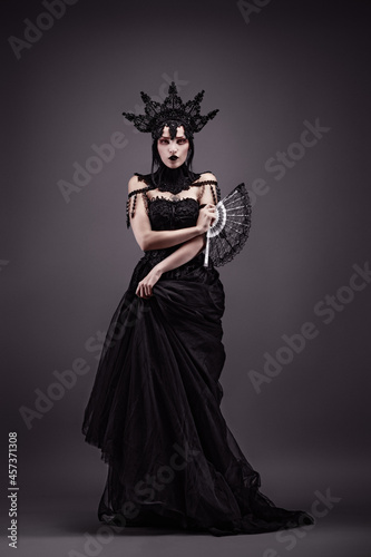 Fotografie Attractive young woman wearing a black dress, a crown and a fan