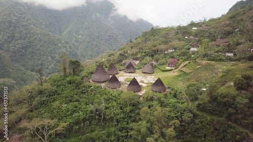 Aerial view of Traditional houses in Wae Rebo village in the jungle, Flores, Indonesia. Famous Manggarai's traditional villages, consist of 7 custom houses. 4K drone footage flying over the village. photo
