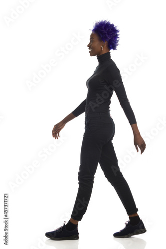 African American Woman Is Walking In Black Clothes. Full Length, Side View.