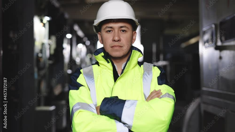 Portrait of confident engineer wearing safety vest and hard hat crossing arms at electrical control room. Confident pose of worker in safety uniform look to camera Portrait of confident engineer wearing safety vest and hard hat crossing arms at electrical control room. Confident pose of worker in safety uniform look to camera