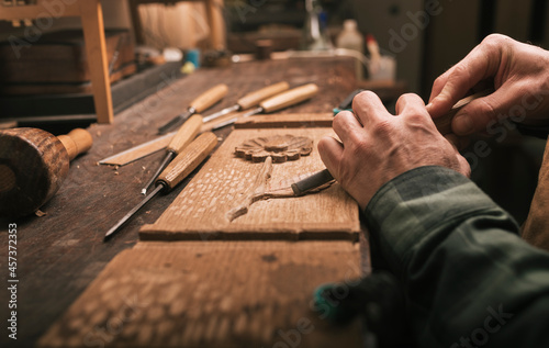 Close up of cabinetmaker working on a wood carving with a chisel. photo