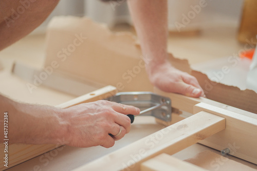 House furniture assembly process, hands of a man with a screwdriver photo