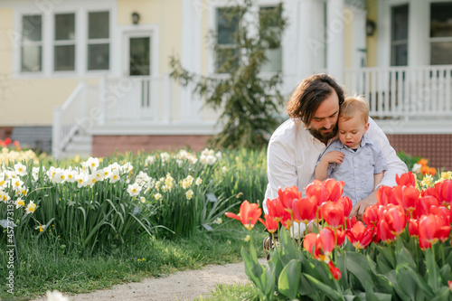 Father teaching toddler son about flowers in tulip garden photo