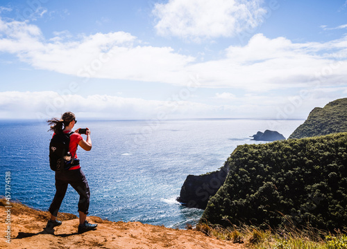 Woman takes cell phone picture while hiking near ocean in Hawaii photo