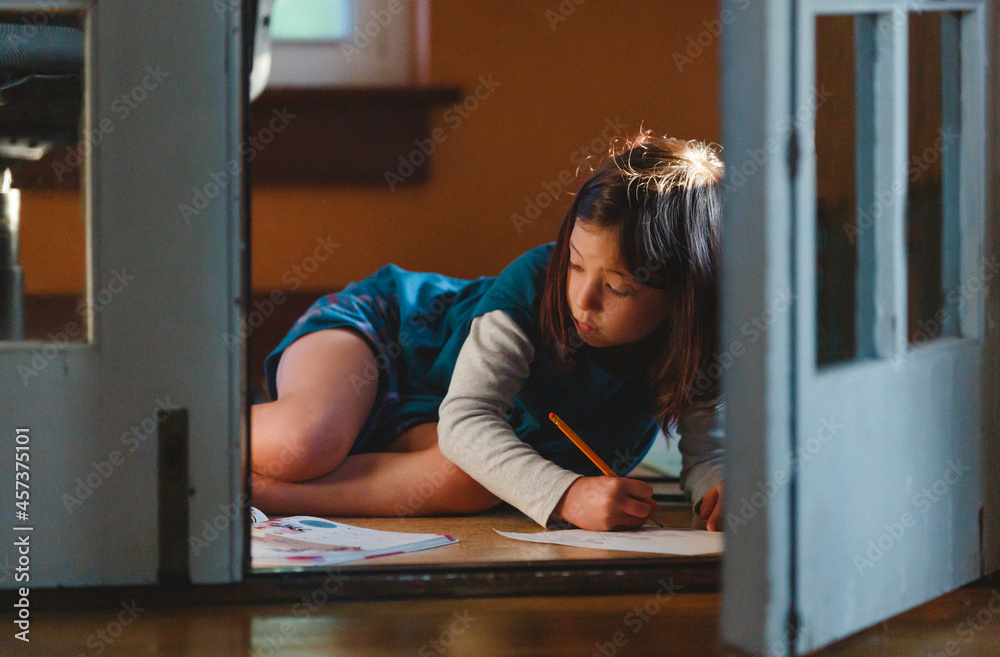 View through French doors of child drawing on floor in beautiful light View through French doors of child drawing on floor in beautiful light