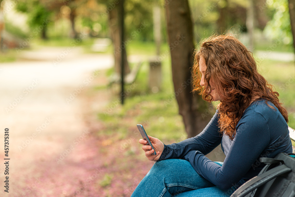 Portrait of charming red haired young woman with smartphone in a park Portrait of charming red haired young woman with smartphone in a park