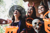 amazed kids in creepy costumes holding buckets near mom with halloween cookie
