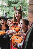 kids in creepy halloween costumes growling at blurred parents with candies