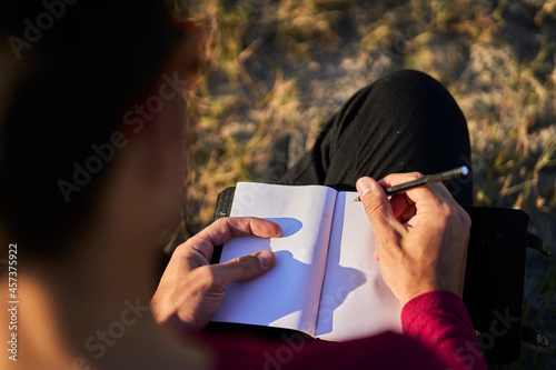 young man writing on the beach photo