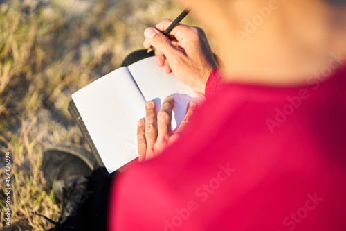 young man writing on the beach photo