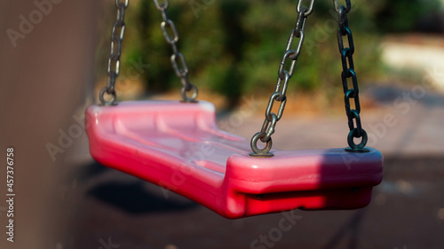 A red plastic swing in a park © Calin
