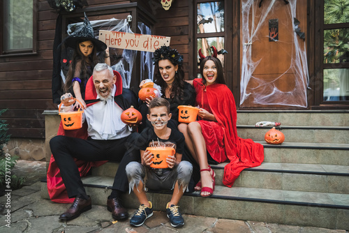 фотографія parents and kids in creepy halloween costumes grimacing while sitting on cottage