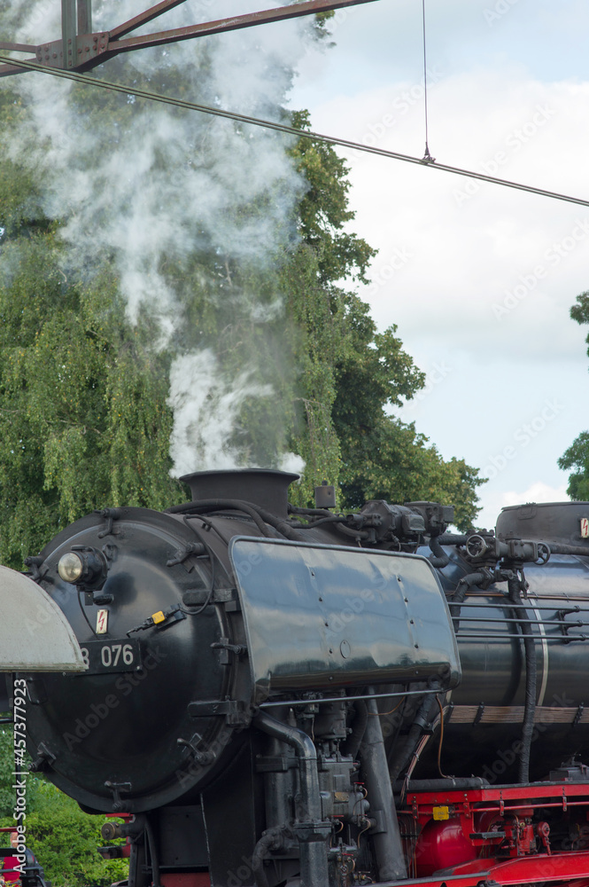 Naklejka premium Detail of a old historic steam black locomotive with smoke at station Dieren in the Netherlands