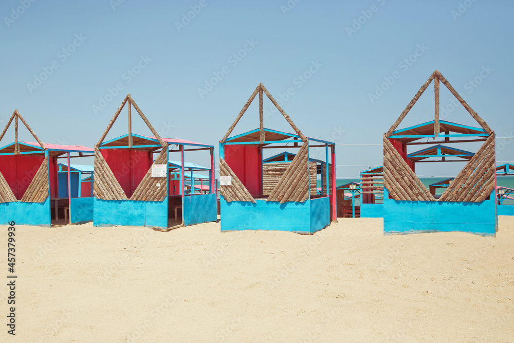 Houses on the beach of Caspian Sea . Summer Background . the seaside . wooden houses by the beach in Caspian Sea . Cabins at the sand beach. Sea sand . Beach huts . Houses on the beach of Caspian Sea . Summer Background . the seaside . wooden houses by the beach in Caspian Sea . Cabins at the sand beach. Sea sand . Beach huts .