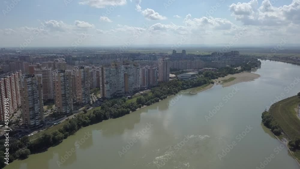 aerial view - flight over a wide flat river along the coast, on which there are multi-storey modern buildings of the city of Krasnodar. A sunny day in early autumn. D-cinelike format aerial view - flight over a wide flat river along the coast, on which there are multi-storey modern buildings of the city of Krasnodar. A sunny day in early autumn. D-cinelike format