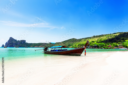 Thai traditional wooden longtail boat and beautiful sand beach at Koh Phi Phi island in Thailand.