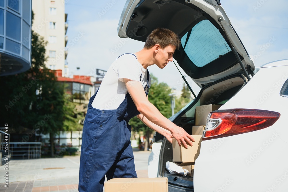 Smiling delivery man standing in front of his car Smiling delivery man standing in front of his car