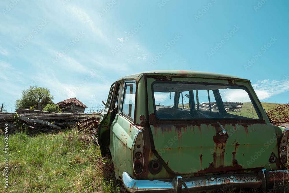 Old rusty family green car in a grass nature field on a sunny day Old rusty family green car in a grass nature field on a sunny day