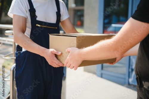 Delivery man service with boxes in hands standing in front of Customer's house doors
