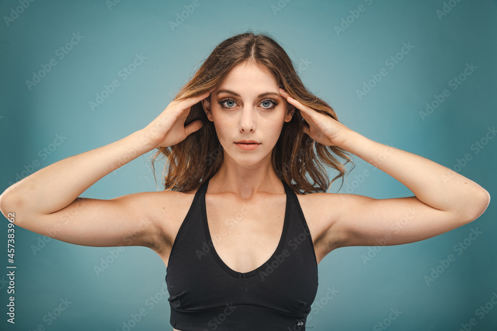 Young Woman with Blue Eyes and Brown Hair poses before a Blue Background