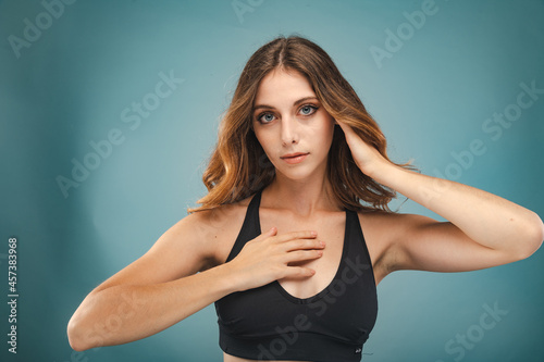 Young Woman with Blue Eyes and Brown Hair poses before a Blue Background photo