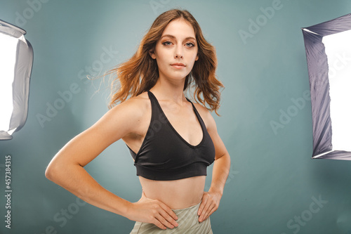 Young Woman with Blue Eyes and Brown Hair poses before a Blue Background photo