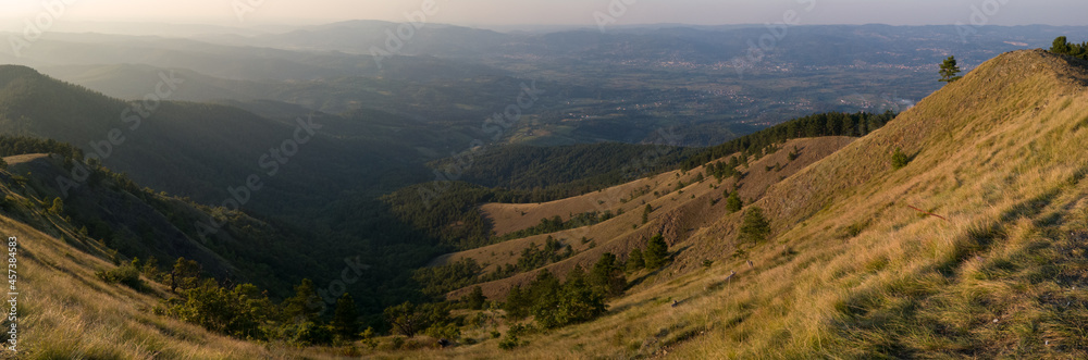 View from the top of Gostilj on the mountain Ozren on the slopes and villages in the valley, a landscape of hilly Balkans with haze on the horizon at evening