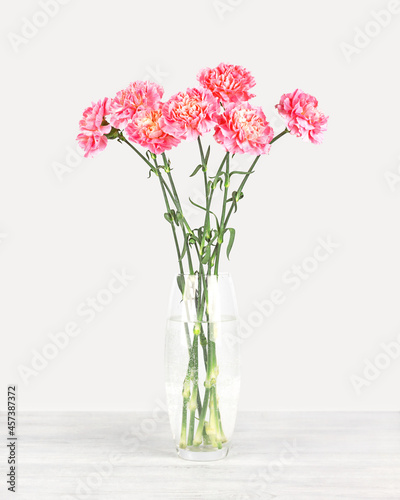 Bouquet of carnations in a glass vase on a gray background. Front view. © Flena_13