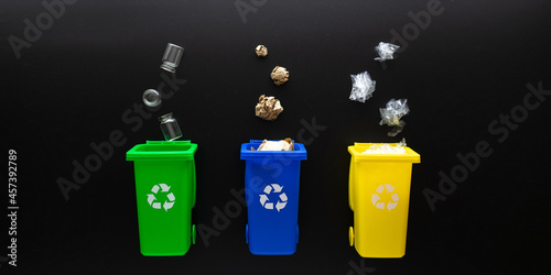 Recycling set bins. Yellow, green, blue dustbin for recycle plastic, paper and glass can trash on black background. Container for disposal garbage waste and save environment. Flat lay.