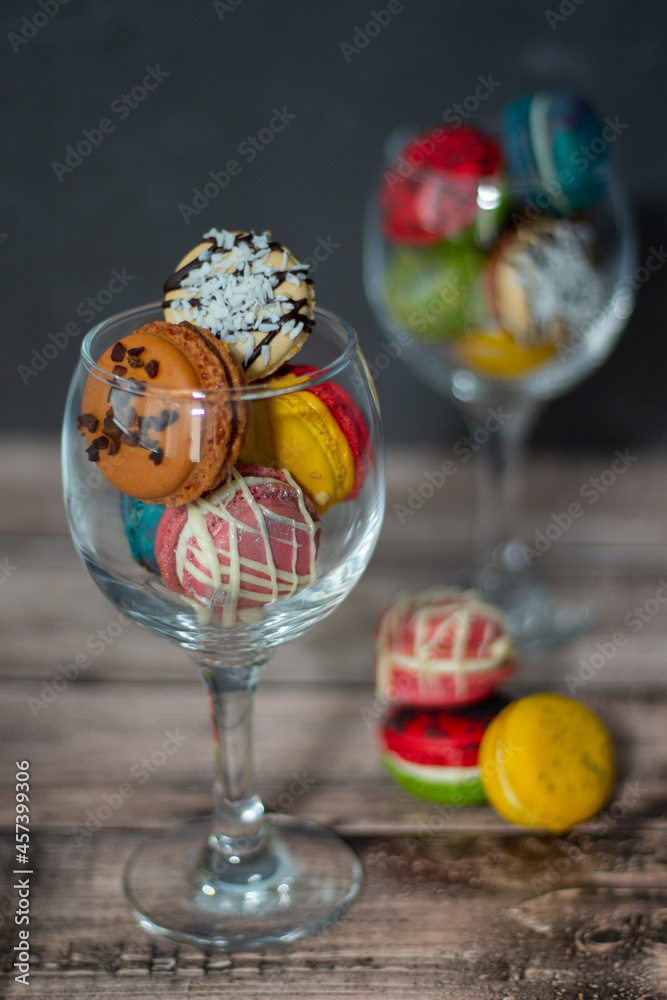 Elegant wine glasses filled with an array of vibrant macarons, poised on a wooden surface, oozing sophistication and charm. Elegant wine glasses filled with an array of vibrant macarons, poised on a wooden surface, oozing sophistication and charm.