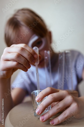 a girl in goggles conducts chemical experiments at home