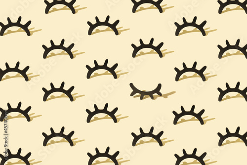 Creative pattern with wooden eyelashes on a pastel yellow backgr