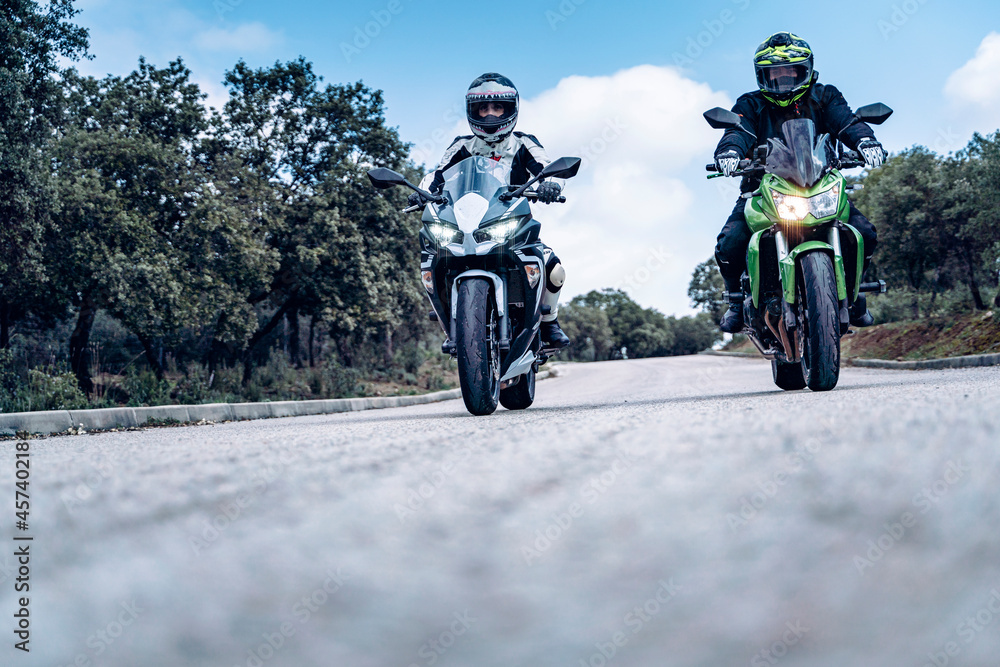 biker couple riding along a mountain road with their sport bikes biker couple riding along a mountain road with their sport bikes