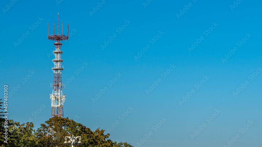 the TV and radio tower with antennas of cellular communication on the blue sky background. Space for text.