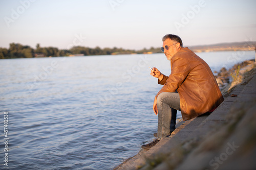 Obraz na płótnie lonely man sitting on stairs next to the river bank