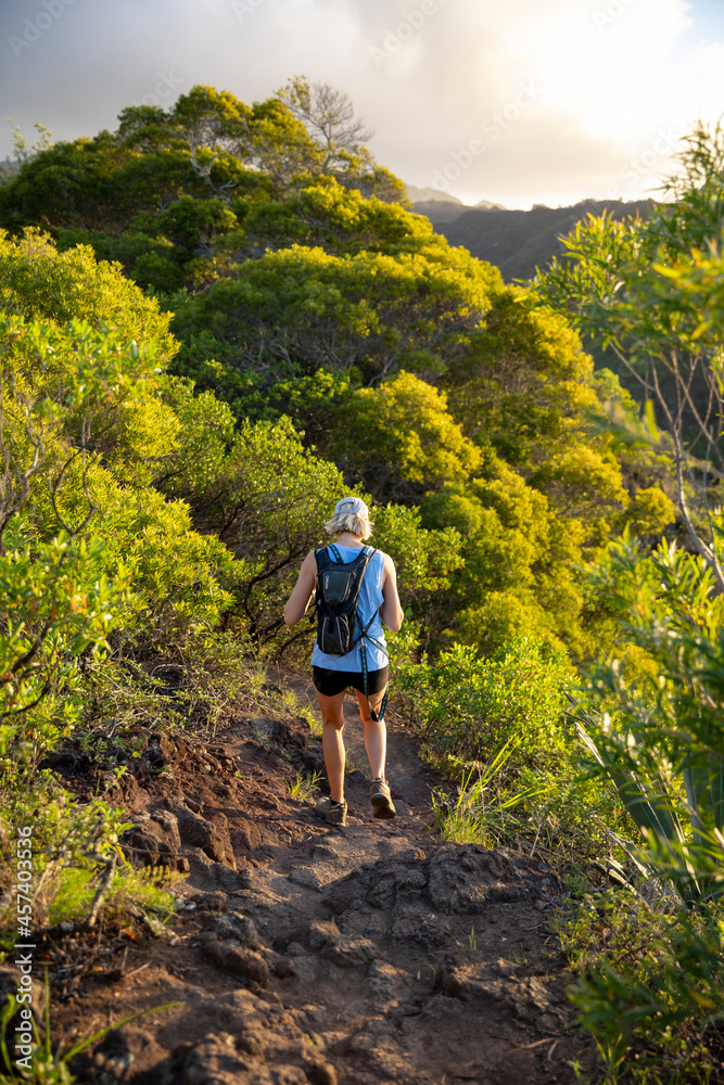 Adventurous blonde woman hiking down a rocky trail in Hawaii