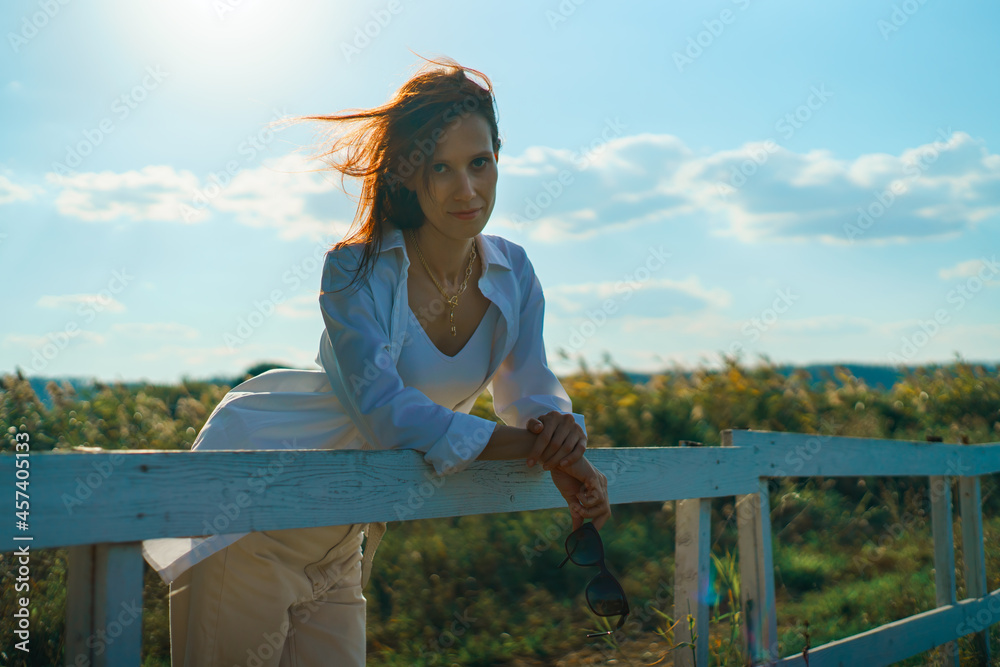 Woman relaxing on ranch and enjoying field view agricultural landscape in farm in sunset